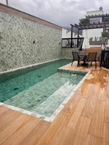 a swimming pool with a table and chairs on a wooden floor at Casa aconchegante in Maresias