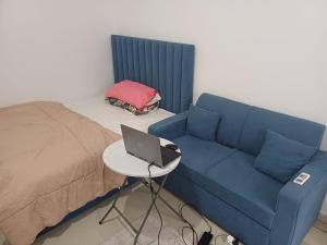 Zimmer mit einem Sofa und einem Tisch mit einem Laptop in der Unterkunft Fully Furnished Modern Studio in a Prime Location beside Abu Dhabi Central Bus Station and Al Wahda Mall العربية استوديو حديث ومفروش بالكامل في موقع مميز بجوار محطة الحافلات المركزية ومول الوحدة في أبوظبي in Abu Dhabi