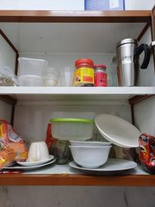 ein Regal mit Platten, Schalen und anderen Küchenutensilien in der Unterkunft Fully Furnished Modern Studio in a Prime Location beside Abu Dhabi Central Bus Station and Al Wahda Mall العربية استوديو حديث ومفروش بالكامل في موقع مميز بجوار محطة الحافلات المركزية ومول الوحدة في أبوظبي in Abu Dhabi