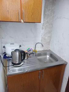 eine Küchenspüle mit einer Teekanne drauf in der Unterkunft Fully Furnished Modern Studio in a Prime Location beside Abu Dhabi Central Bus Station and Al Wahda Mall العربية استوديو حديث ومفروش بالكامل في موقع مميز بجوار محطة الحافلات المركزية ومول الوحدة في أبوظبي in Abu Dhabi + 39 Fotos