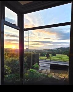 an open window with a view of a sunset at Wharfe View Cottage Ilkley in Ilkley