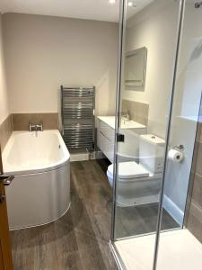 a bathroom with a tub and a toilet and a sink at Tern Place in Kelling