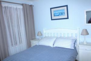 a bedroom with a bed and two night stands and two lamps at South Peninsula Coastal Apartment in Cape Town