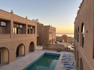 a view of a building with a pool and chairs at Wazidi Resort in Siwa