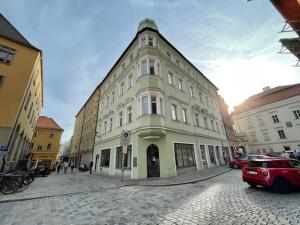 ein großes Gebäude auf einer Stadtstraße mit einem roten Auto in der Unterkunft Cityappartment am Regensburger Dom in Regensburg
