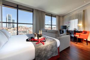 a hotel room with a large bed and a living room at Crisol Vía Castellana in Madrid +26 photos