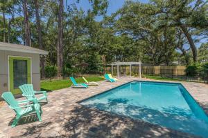 a swimming pool with chairs and a gazebo at Sweetpeas Cottage in Jekyll Island