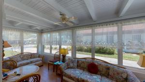 a screened in porch with couches and a ceiling fan at Barronhaus in Jekyll Island