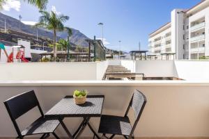 einen Balkon mit 2 Stühlen und einem Tisch mit einer Pflanze in der Unterkunft Brisa - Armonía Park, Bajamar in El Puertito