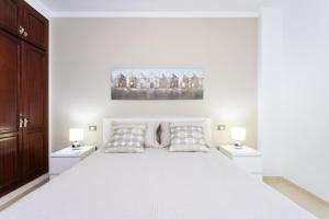 ein weißes Schlafzimmer mit einem großen Bett mit zwei Nachttischen in der Unterkunft Brisa - Armonía Park, Bajamar in El Puertito