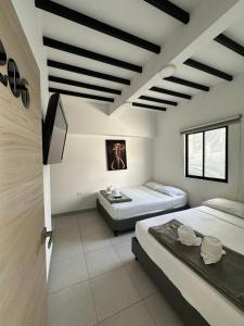 a room with two beds and a tv in it at HOTEL BLUE GUATAPE in Guatapé