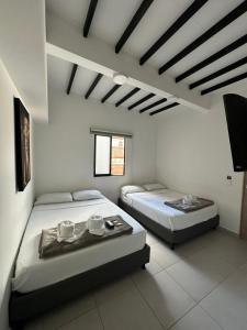 two beds in a room with white walls at HOTEL BLUE GUATAPE in Guatapé