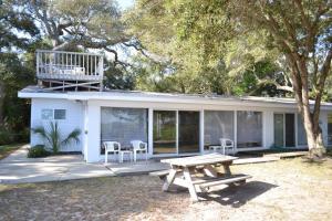 een wit huis met een picknicktafel ervoor bij Cottage By The Sea - Unit A in Jekyll Island