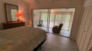 een slaapkamer met een bed, een stoel en een raam bij Cottage By The Sea - Unit A in Jekyll Island