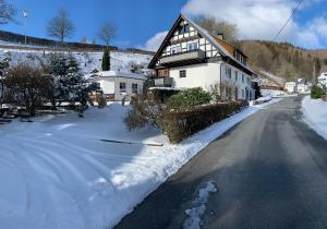 a house with snow on the side of a road at Ferienwohnung Dünnebacke in Schmallenberg
