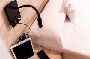 ein Tablet, das an einer Wandsteckdose neben einem Bett angeschlossen ist in der Unterkunft Hotel Bersoca in Benicàssim