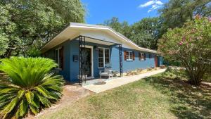 een klein blauw huis in een tuin met bomen bij Kisses Cottage in Jekyll Island