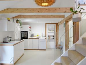 Una cocina con gabinetes blancos y una escalera. en The Nest at Severels, en North Mundham