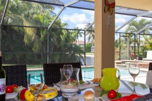 ein Tisch mit Essen und Weingläsern und einem Pool in der Unterkunft Ellen`s House-pool and Jacuzzi, Gulf access in Matlacha