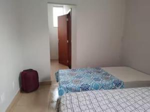 a room with two beds and a suitcase on the floor at Casa de Carolinda in Uberaba