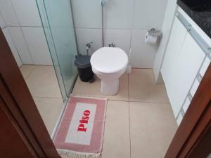 a bathroom with a toilet and a pink rug at Casa de Carolinda in Uberaba