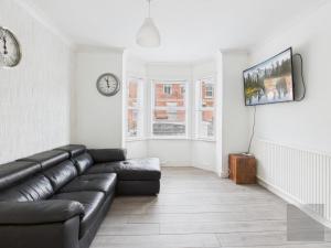 a living room with a couch and a clock on the wall at 3 Bed House in Reading Area in Reading