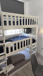 two white bunk beds in a room with a chair at Trio Den in Zone 2 - Willesden Green in London