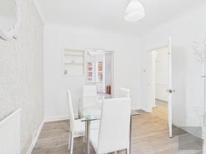 a white dining room with a glass table and white chairs at 3 Bed House in Reading Area in Reading +3 photos