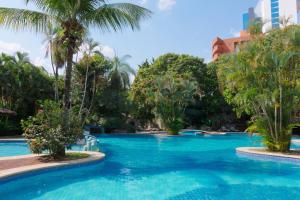 a swimming pool with blue water and palm trees at Hotel Camino Real in Santa Cruz de la Sierra