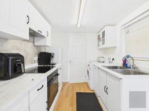 a white kitchen with a sink and a microwave at 3 Bed House in Reading Area in Reading