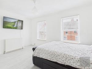 a white bedroom with a bed and two windows at 3 Bed House in Reading Area in Reading