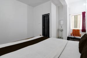 a bedroom with a white bed and a window at Hotel O Shree Guest House in Khandagiri