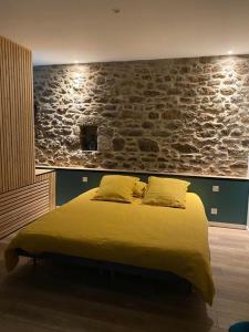ein Schlafzimmer mit einem gelben Bett und einer Steinmauer in der Unterkunft La parenthese in Beaussais sur Mer