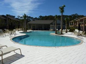 a large swimming pool with chairs and palm trees at Honu Kai in Jekyll Island