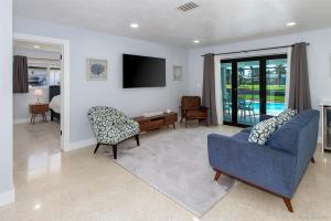 Una sala de estar con un sofá azul y un televisor en Hidden Gem-Walking Distance to Downtown Cape Coral, en Cabo Coral