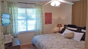 a bedroom with a bed and a television and a window at Ariel West Duplex in Jekyll Island