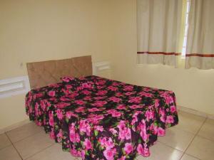 - une chambre avec un lit recouvert de fleurs roses dans l'établissement Apartamento Acolhedor, à Uberaba