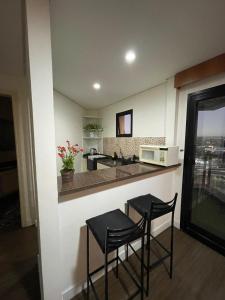 eine Küche mit zwei Hockern an einer Theke mit einer Mikrowelle in der Unterkunft Flat - Excelente localização e vista espetacular in São José dos Campos