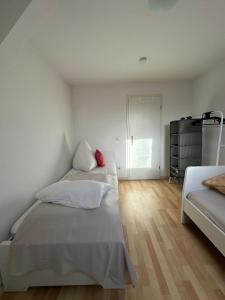 two beds in a room with white walls and wooden floors at 64qm für 3 Personen in Niederdorla