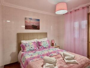 a bedroom with a large bed with pink sheets and pillows at Nazaré Stay Home - Alecrim T2 in Nazaré