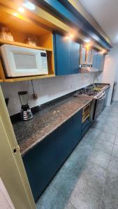 une cuisine avec des armoires bleues et un micro-ondes blanc dans l'établissement Beautiful apartment in the colonial area of Chacao, à Caracas