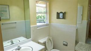 a bathroom with a toilet and a sink and a mirror at Ariel East Duplex in Jekyll Island +21 photos