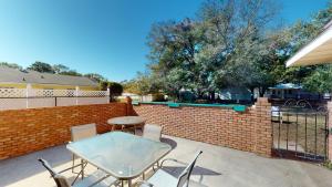 a patio with a table and chairs and a brick fence at Turtle's Nest Duplex in Jekyll Island