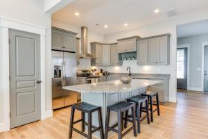 a kitchen with white cabinets and a large island with bar stools at 408A The Boardwalk House in Virginia Beach