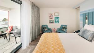 um quarto com uma cama e cadeiras e uma varanda em Hotel Indigo Torquay, By IHG em Torquay