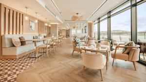 a restaurant with tables and chairs and windows at Hotel Indigo Torquay, By IHG in Torquay