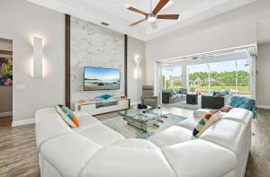 Una sala de estar con un sofá blanco y un televisor. en Kokomo-Modern Home with Tiki Hut, en Cabo Coral