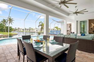 comedor con mesa, sillas y piscina en Kokomo-Modern Home with Tiki Hut, en Cabo Coral