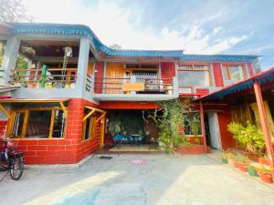 a red brick house with a balcony and a patio at Neer Stays Munsyari in Munsyari