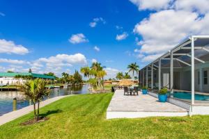 una casa con patio junto a un cuerpo de agua en Kokomo-Modern Home with Tiki Hut, en Cabo Coral